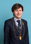 Perth and Kinross Provost Xander McDade with dark brown hair, wearing a navy blue suit and a gold appearing chain of office.