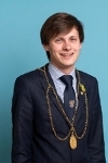 Perth and Kinross Provost Xander McDade with dark brown hair, wearing a navy blue suit and a gold appearing chain of office.